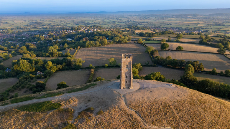Aerial view of Glastonbury Tor with St Michael's Tower surrounded by lush countryside in Glastonbury, Somerset, U.K.