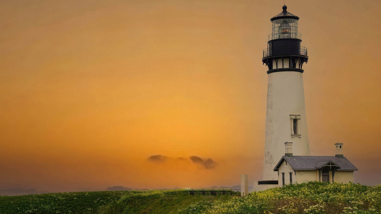 The Yaquina Head Lighthouse in Newport, Oregon, with a cloudy orange sky in the background
