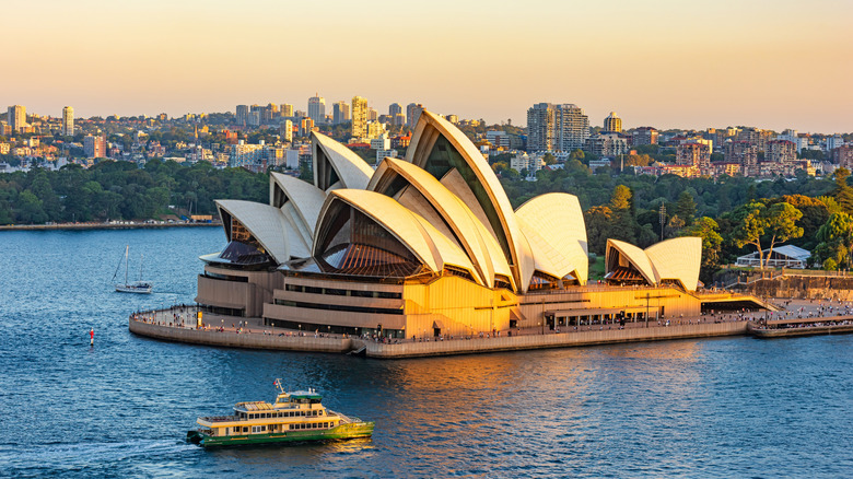 A ferry passes the Sydney Opera House at sunset.