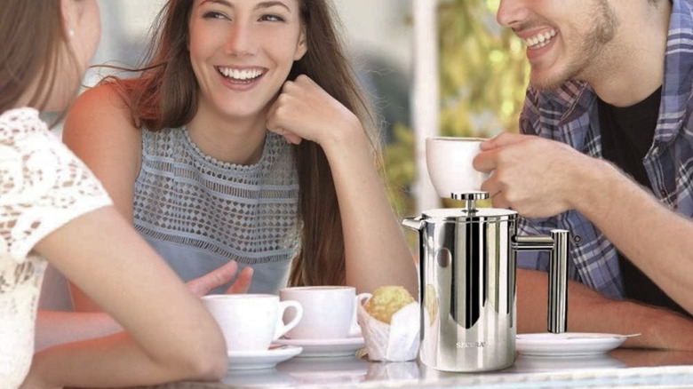 A group of three sitting around a table drinking coffee brewed in a Secura French Press