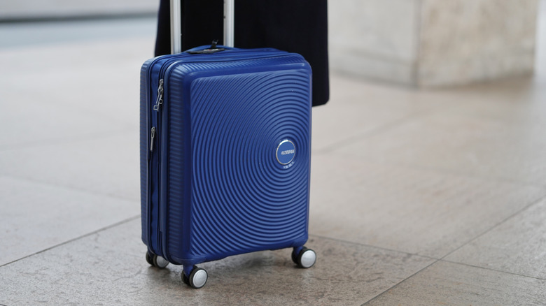 Close-up detail view of a blue American Tourister travel suitcase, during a street style fashion photo session, on December 13, 2025 in Paris, France.