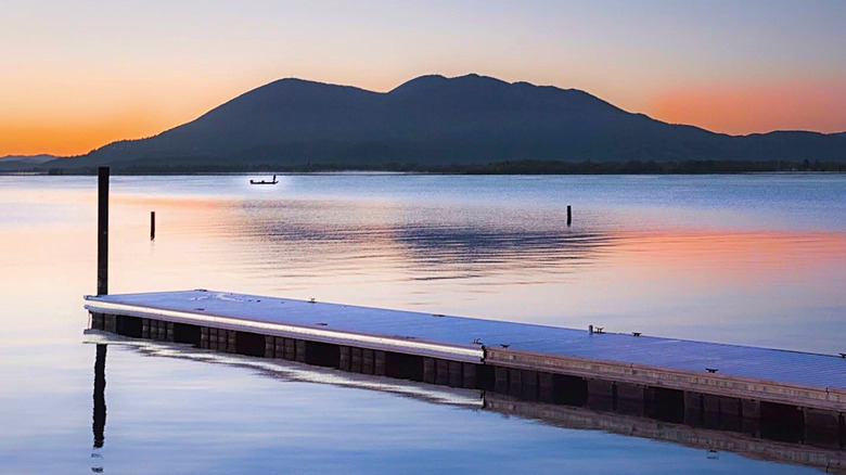 A Clear Lake jetty at sunset with a fishing boat off in the distance.