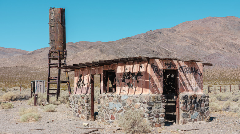 An abandoned cabin in Garlock with an aged water tank beside it
