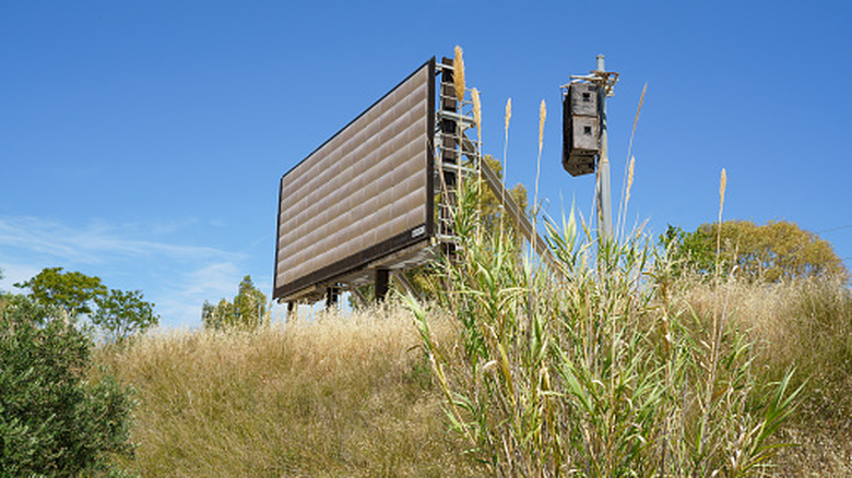 The deactivated screen, grown over by wild grasses sits unused on the abandoned grounds of the 2004 Olympic Canoe rapids in Athens.