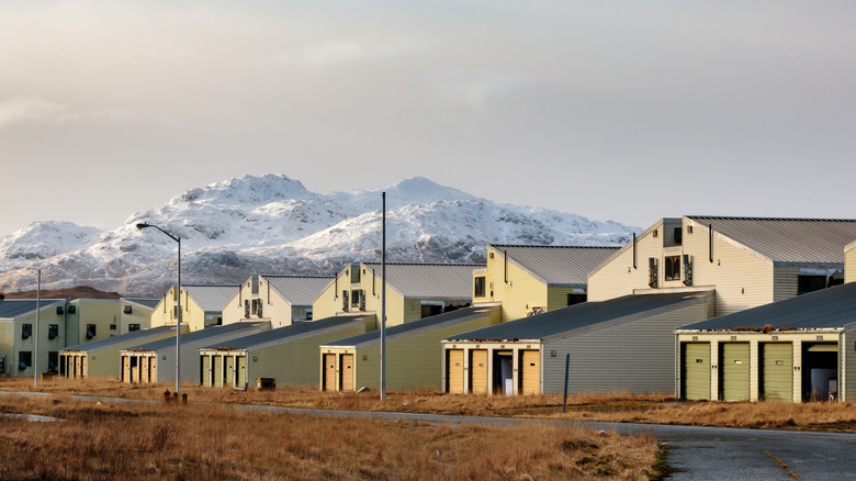 Abandoned military housing on Adak Island, Alaska with snowy mountains in the background