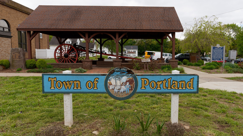 Sign for the Town of Portland stands on Main Street beside the Police Station. The Brownstone Arch sits behind under a protective roof.
