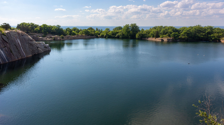 View of lake surrounded by dense trees and old granite quarry at Halibut Point State Park in Rockport, Massachusetts