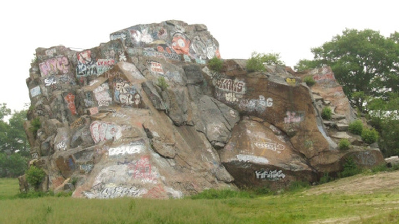 A granite outcropping from an old quarry is covered with grafitti