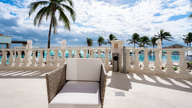 View of seating area at Hyatt Zilara with white umbrellas, palm trees, and pool in the background on a sunny day