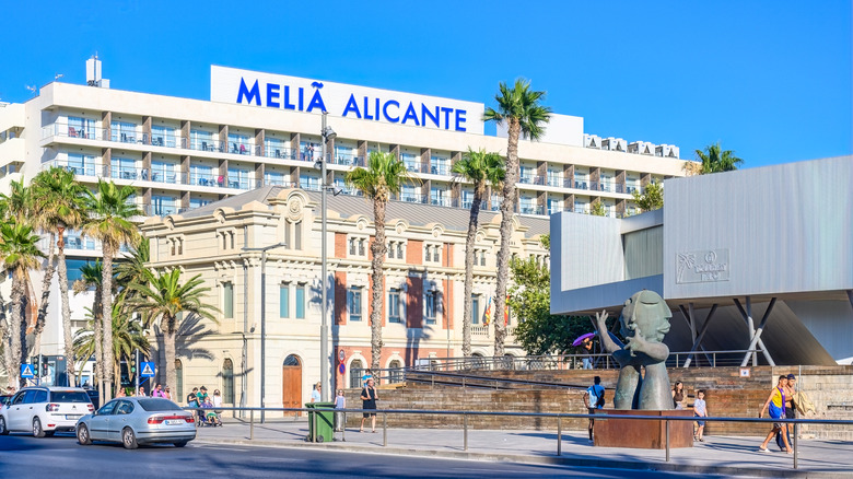 View of the Melia Alicante hotel with palm trees are around the building, taken from across the street
