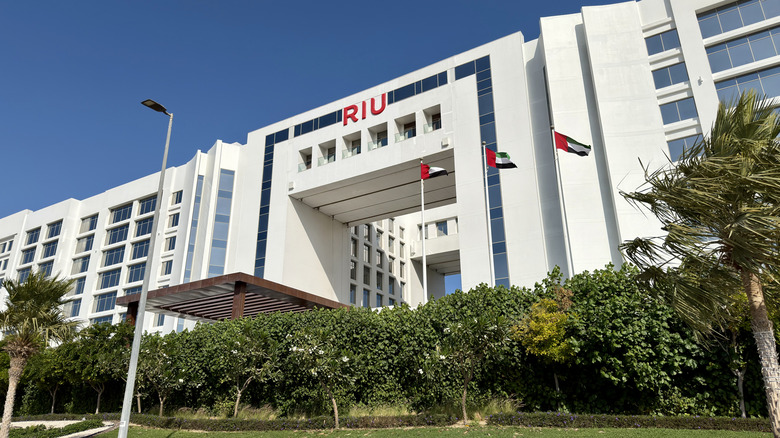 View of Hotel Riu Dubai with foliage in front and a line of UAE flags