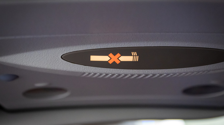 An overhead no smoking sign inside airplane
