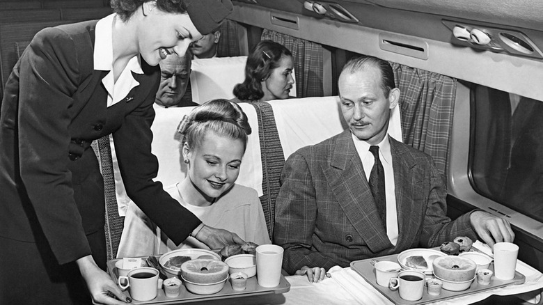 A stewardess serves a meal to a couple on an American Airlines flight, mid to late 1950s.