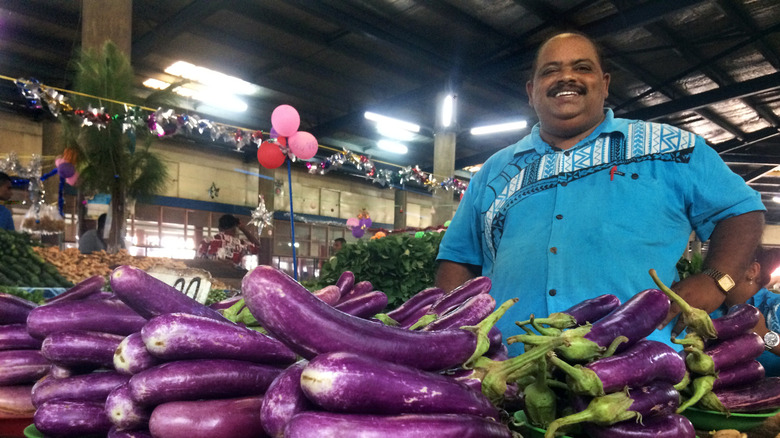 A Fijian man selling eggplants in a market