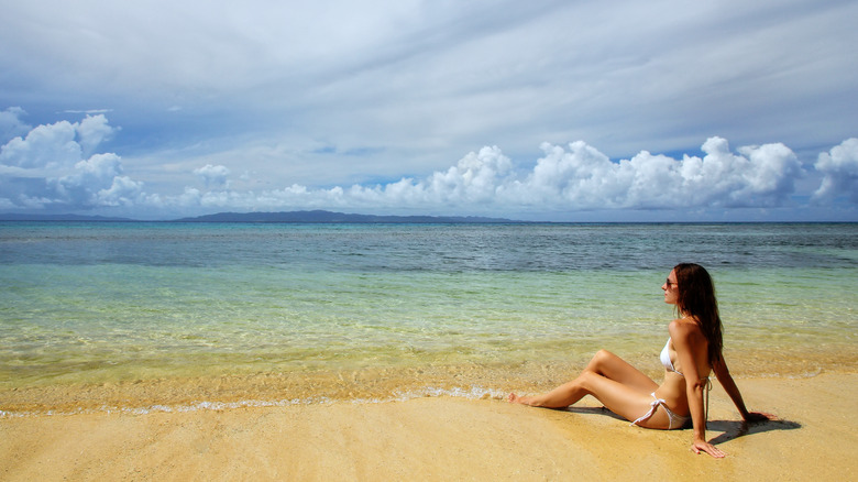 A woman lounging on a beach in Tauveni, Fiji