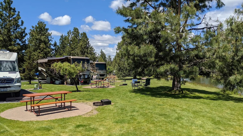 A green lawn and picnic table next to large motorhomes at Bend/Sisters Garden RV Resort in Bend, Oregon