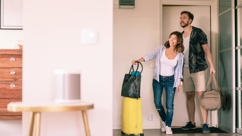Happy vacation rental guests coming through a door with bags