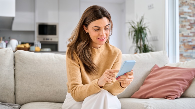 A woman sitting on a couch, looking at her phone