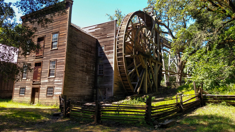 A wooden millhouse with a large waterwheel at Bale Grist Mill State Historic Park in California.