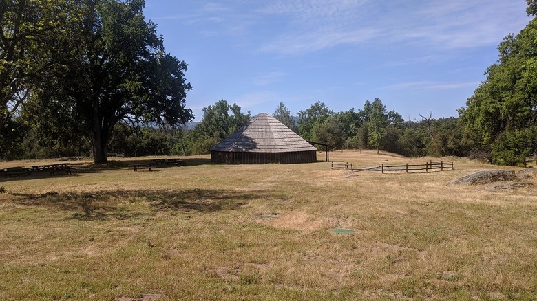 A roundhouse surrounded by oaks and grass at California's Wassama Round House State Historic Park.