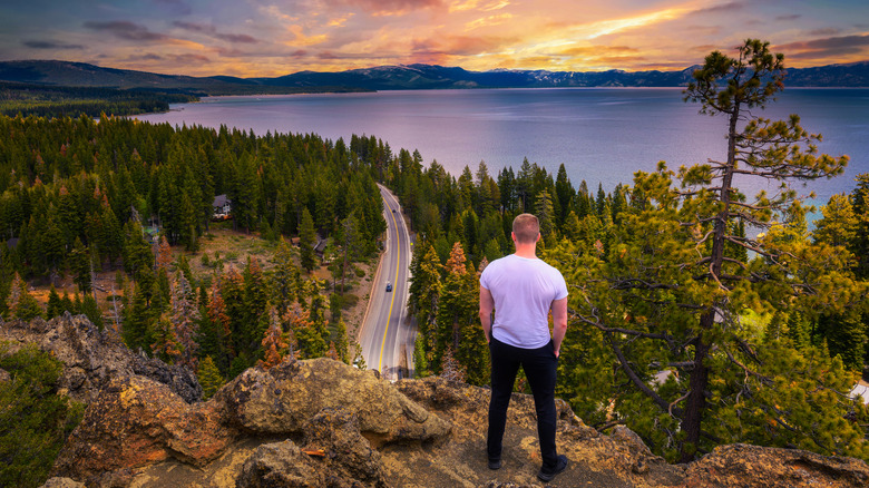 A man looking at the view of Lake Tahoe from the Eagle Rock Viewpoint at sunrise