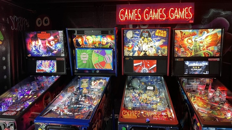 A neon sign reading Games Gams Games and four colorful pinball games