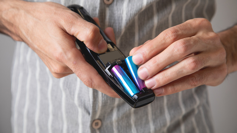 man taking batteries out of TV remote