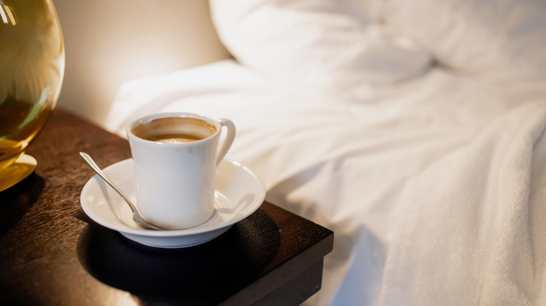 Coffee mug on wooden table next to bed