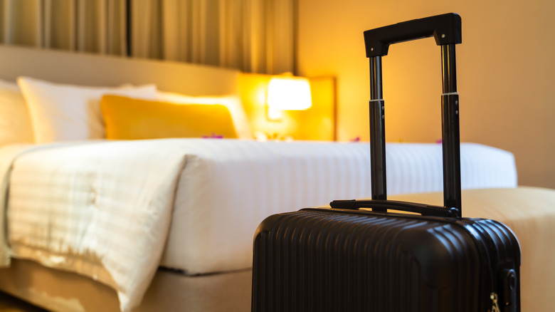 Black suitcase in front of hotel bed