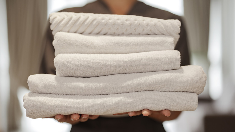 Hotel employee carrying stack of towels
