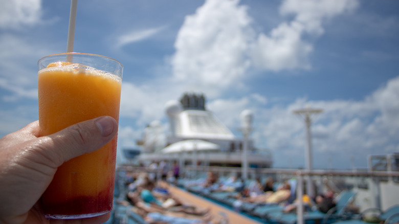 Orange and Mango Cocktail on on a cruise liner being held by a Caucasian mans left hand