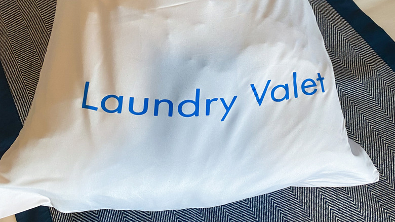 A white bag of laundry in Oceania Cruise stateroom with text "Laundry Valet" in blue