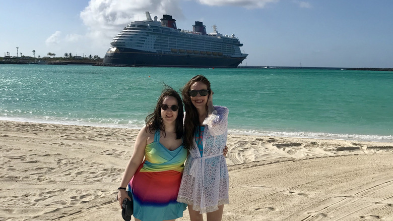 Two female friends at Disney's Castaway Cay on a sunny day with the Disney Dream ship in the background