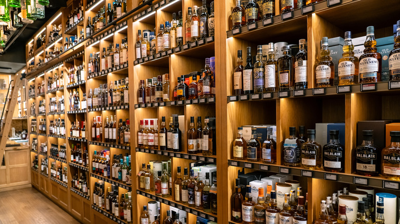 A wall of build-in wood shelves full of Scotch whiskey bottles at a liquor store in London, England