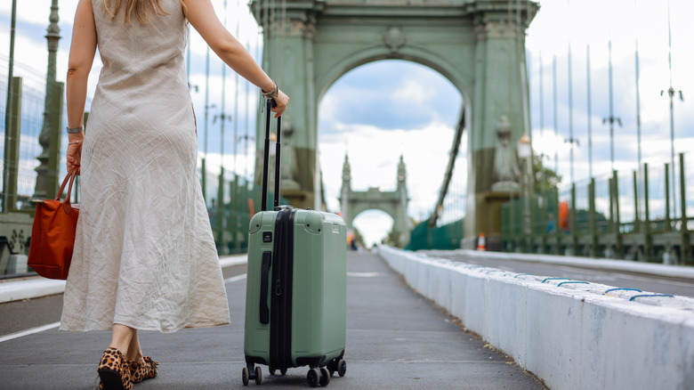 Back view of woman pulling suitcase on the Tower Bridge in London