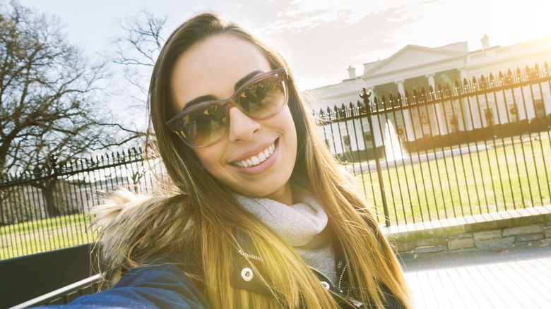 A woman taking a selfie in front of the White House