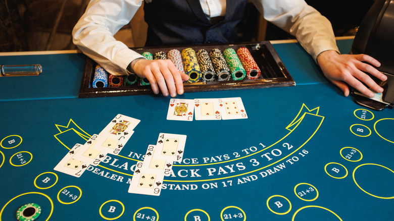 Close-up of a blackjack table with a dealer dealing cards and colorful casino chips arranged on the felt,