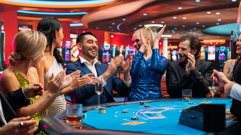 Group of Rich Glamorous People Playing Card at Blackjack Table on a Casino Floor.