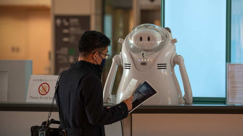 A man talks to a robot on an information desk at Haneda Airport on November 30, 2021 in Tokyo, Japan.