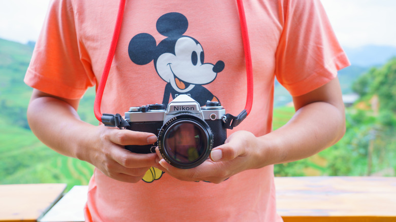 Someone holding a Nikon camera wearing a Mickey Mouse t-shirt