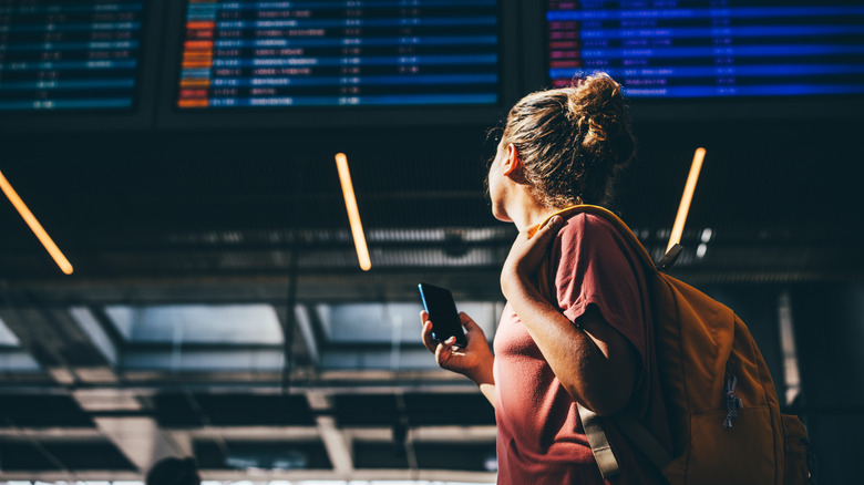 woman looking at departure board in airport