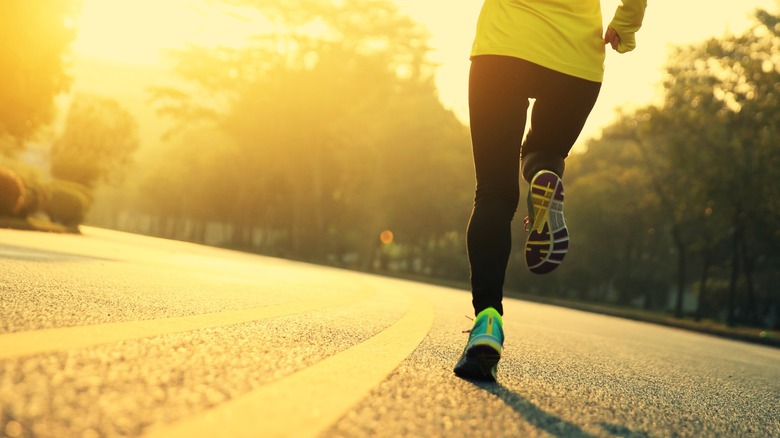 A runner traveling down a road in the sun