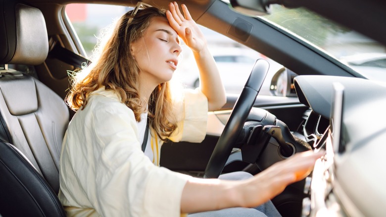 A woman feeling poorly from the summer heat while in her vehicle