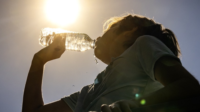 A woman hydrating with water in the summer heat