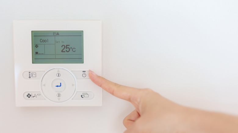 A hand pointing at the thermostat