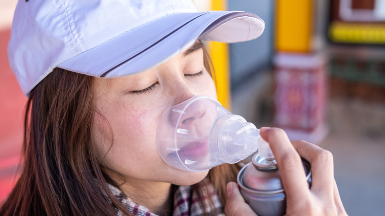 A woman using canned oxygen