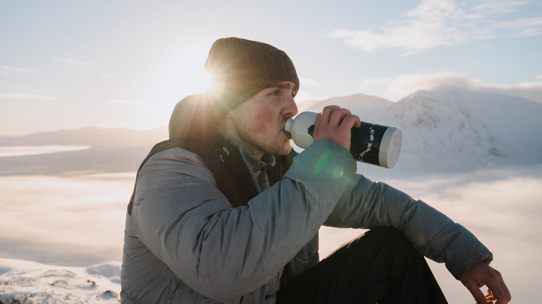 A man drinking water on a mountain