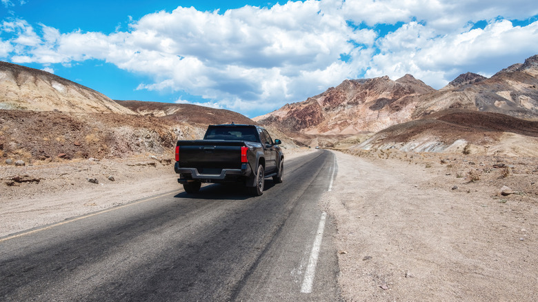A black pickup drives along Artists Drive in Death Valley National Park