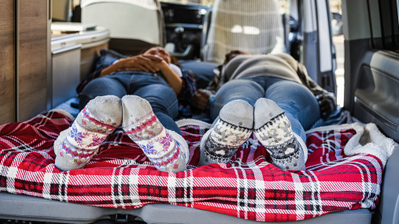 Mature women sleeping inside mini van camper wearing warm socks