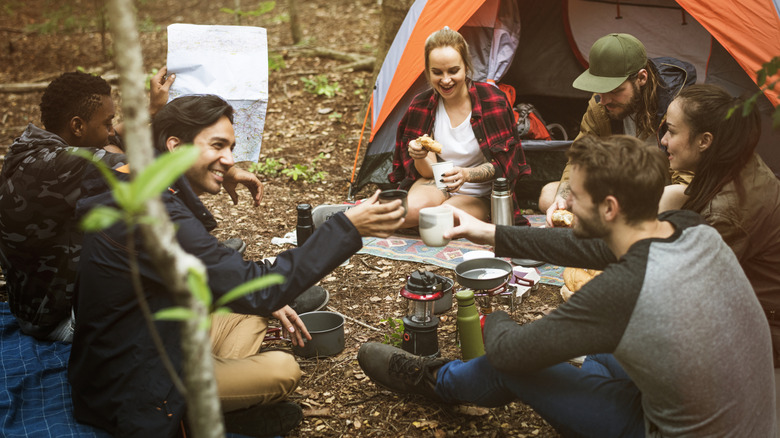 Friends camping together, sitting outside of a tent